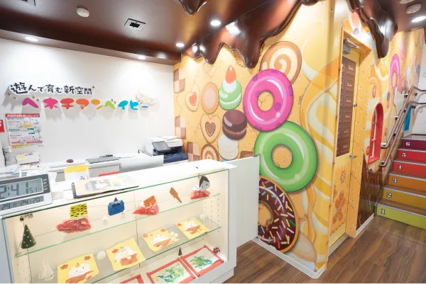 ベネチアンベイビー外観。「遊んで育む新空間 ベネチアンベイビー」とあり、壁紙はチョコレートやクッキー、ドーナツなどをあしらったポップなものになっている