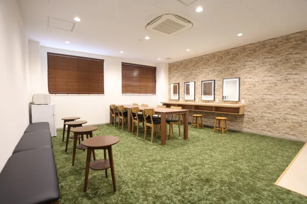 ソファや椅子、机などが設置された休憩室。床は緑色のカーペットに見え、全体的に落ち着いた印象を感じる