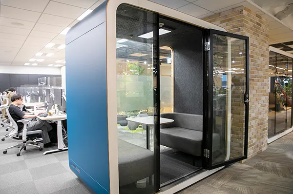 1on1ブース。テーブルを挟んでソファが2脚あり、両サイドはドアも含め透明になっている