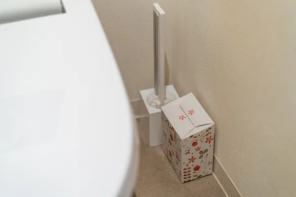 洋式便器の奥、トイレブラシの隣に置いてあるサニタリーボックス